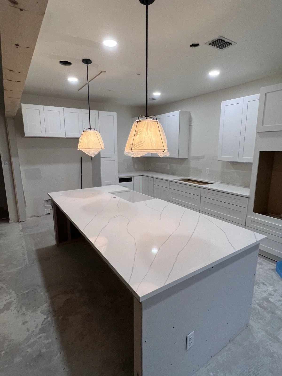 White kitchen with a Calacatta look quartz waterfall island and pendant lights