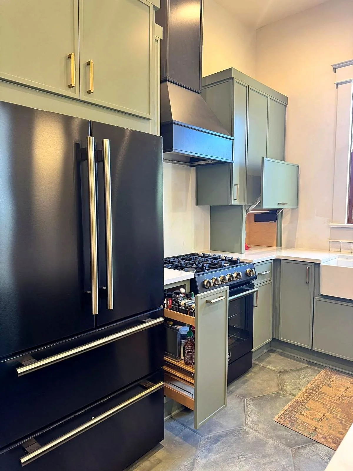 Two tone navy and sage green kitchen cabinets with a black range