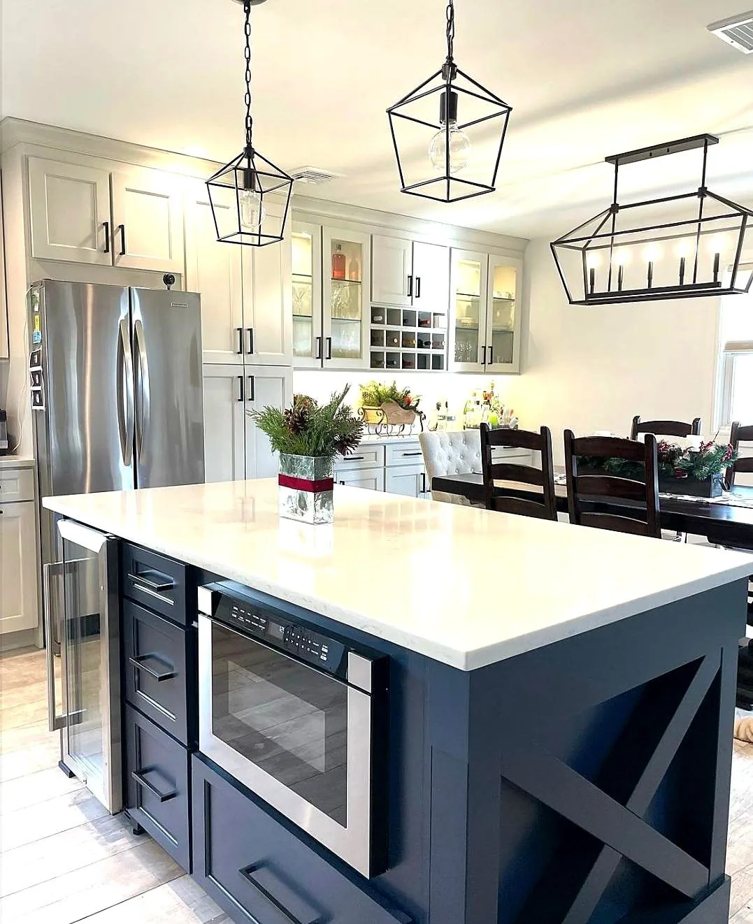 White kitchen with a navy island, lantern pendants and built in island microwave